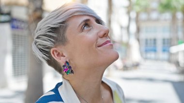 Young woman smiling confident looking to the sky at street