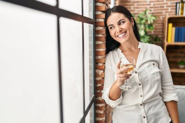 Genç, güzel, İspanyol bir kadın. Evde durup bir kadeh şarap içiyor.