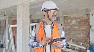 İnşaat alanında Touchpad kullanan orta yaşlı bir inşaatçı.