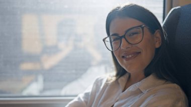 Genç, güzel İspanyol kadın gülümsüyor, mutlu bir şekilde vagonda oturuyor.