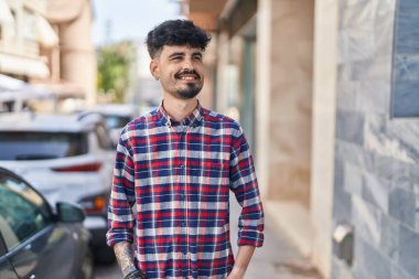 Young hispanic man smiling confident looking to the side at street