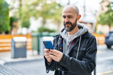 Sokakta akıllı telefon kullanarak kendine güvenen genç kel adam.