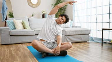 Genç latin adam evde gerinerek yoga eğitimi alıyor.