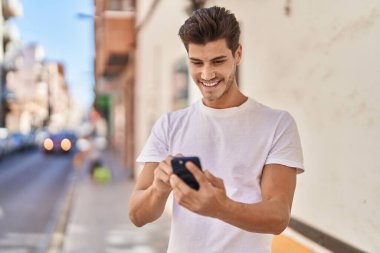 Parkta akıllı telefon kullanarak gülümseyen İspanyol genç adam.