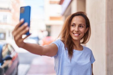 Young woman smiling confident making selfie by the smartphone at street