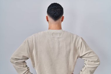 Genç yakışıklı adam izole edilmiş arka planda dikiliyor geriye bakıyor kollarını vücuduna dikiyor. 