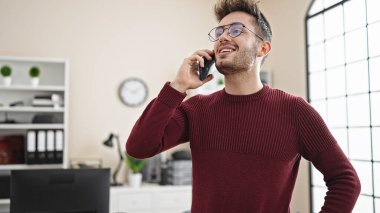 Genç İspanyol iş adamı ofiste çalışan akıllı telefondan konuşuyor.