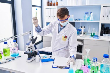 Tıp maskesi takan genç bilim adamı laboratuarda çalışıyor.