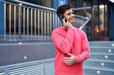 Genç İspanyol adam gülümsüyor. Kendine güveniyor. Sokakta akıllı telefondan konuşuyor.