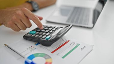 Ofiste hesap makinesi kullanan İspanyol bir iş adamı.