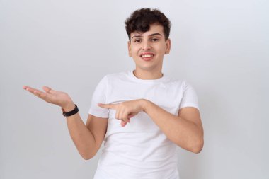 Gündelik beyaz tişört giyen genç adam kameraya hayret ediyor ve gülümsüyor.. 