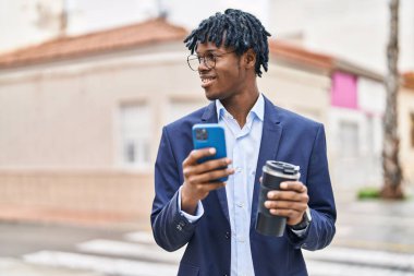 African american man executive using smartphone drinking coffee at street
