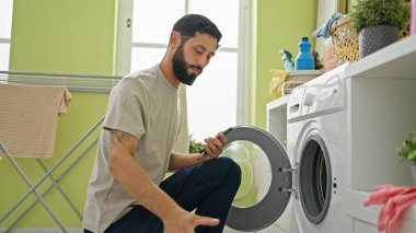 Çamaşırhanede çamaşır yıkayan İspanyol genç adam.