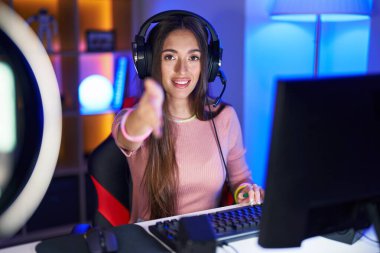 Genç İspanyol kadın video oyunları oynuyor. Arkadaşça gülümsüyor. Karşılama ve hoş geldin demek için tokalaşıyor. başarılı iş. 