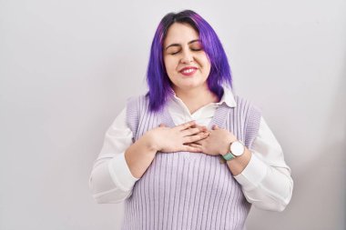 Artı, beyaz arka planda duran, elleri göğsünde, gözleri kapalı ve yüzünde minnet dolu bir jest olan mor saçlı bir kadın. sağlık kavramı. 