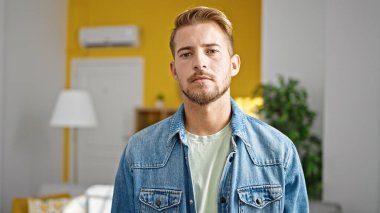 Evinde ciddi bir ifadeyle duran beyaz bir genç.