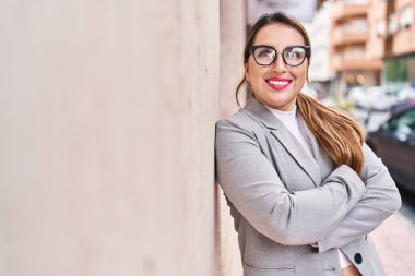 Young beautiful hispanic woman business worker smiling confident standing with arms crossed gesture at street