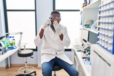 Afrika kökenli Amerikalı bir adam bilim adamının laboratuarında çalışıyor. Telefonda konuşuyor. Ağzı eliyle kapatıyor, şok geçiriyor ve hata yapmaktan korkuyor. şaşırmış ifade 