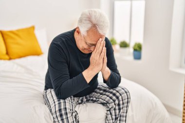 Senior man stressed sitting on bed at bedroom