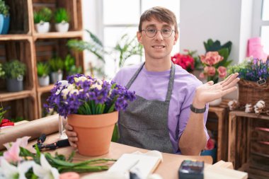 Çiçekçide çalışan beyaz tenli sarışın bir adam avuç içi açık bir şekilde fotokopi alanını gösteriyor, gülümseyerek mutlu bir gülümseme sunuyor. 