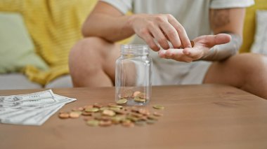 Genç İspanyol adam parktaki şişeye bozuk para yerleştiriyor.