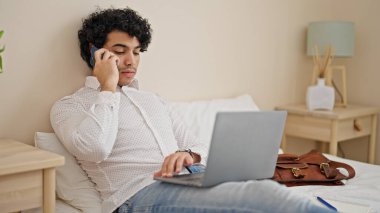 Genç Latin iş adamı otel odasında bilgisayarla konuşuyor.