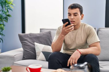 Genç adam kahvaltısını evde akıllı telefon kullanarak yapıyor.