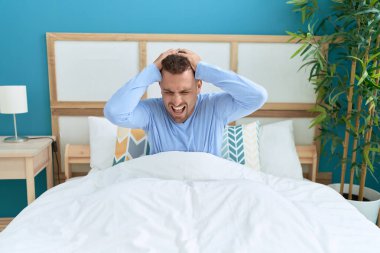 Genç İspanyol adam yatakta oturmuş yatak odasında bağırıyor.