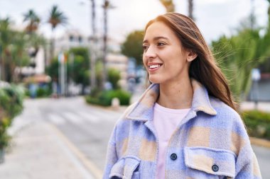 Young beautiful hispanic woman smiling confident looking to the side at street