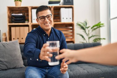 Genç Latin Psikolog Psikoloji kliniğindeki hastaya bir bardak su veriyor.