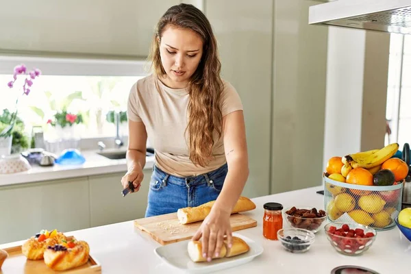 年轻美丽的惊慌失措的女人在厨房切面包 — 图库照片