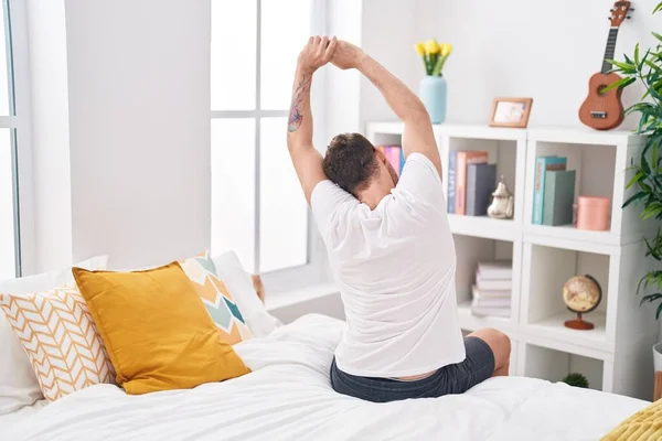 Young Hispanic Man Waking Stretching Arms Bedroom – stockfoto