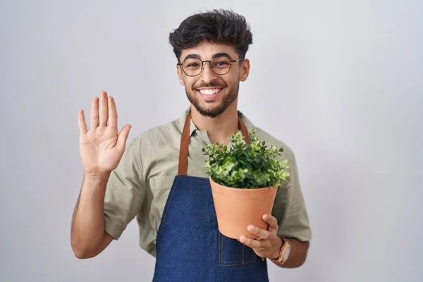 阿拉伯男人拿着绿色的花盆 一边说 一边笑着 友好地欢迎你 — 图库照片