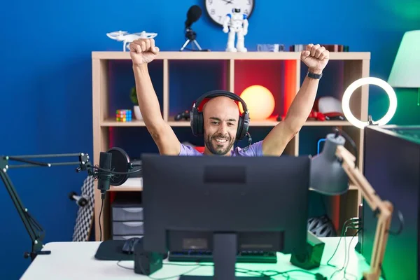 Young bald man streamer playing video game with winner expression at gaming room