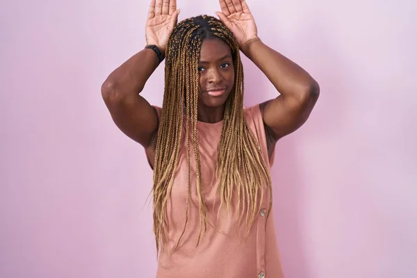 Африканская Американка Плетеными Волосами Стоящая Розовом Фоне Жестикулирующая Заячьими Ушами — стоковое фото