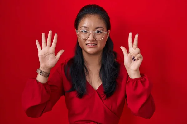 Azjatka Młoda Kobieta Stoi Nad Czerwonym Tle Pokazując Wskazując Palcem — Zdjęcie stockowe