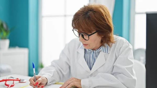 Middle age woman doctor writing medical report, se at clinic