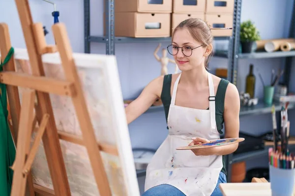 年轻的高加索女艺术家在艺术工作室微笑而自信地画画 — 图库照片