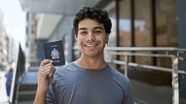 Joven Latino Sonriendo Confiado Sosteniendo Pasaporte Canadiense Calle — Foto de Stock