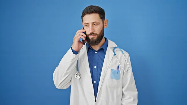 Junger Hispanischer Arzt Spricht Auf Smartphone Vor Isoliertem Blauen Hintergrund — Stockfoto