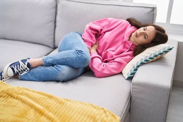 Young Woman Suffering Menstrual Pain Lying Sofa Home - Stock-foto