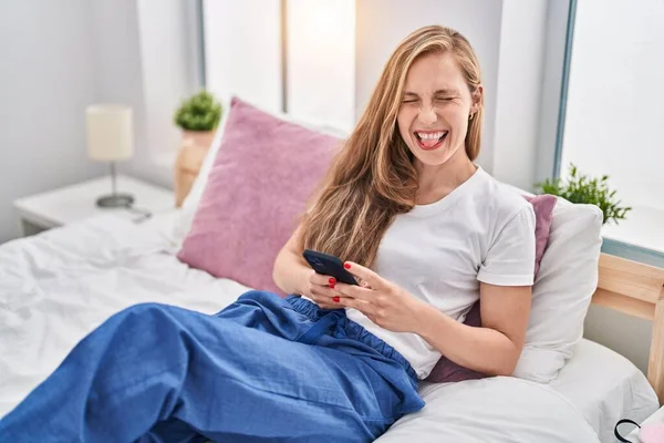 Junge Blonde Frau Mit Smartphone Bett Streckt Zunge Mit Lustigem — Stockfoto