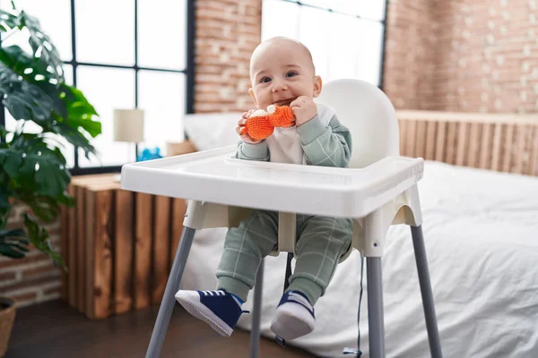愛らしいですCaucasian赤ん坊座っています上の椅子吸いおもちゃにベッドルーム — ストック写真