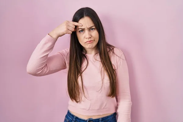 Young Brunette Woman Standing Pink Background Pointing Unhappy Pimple Forehead — Stockfoto
