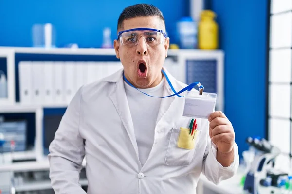Hispanic Young Man Working Scientist Laboratory Holding Card Scared Amazed — Stock Photo, Image