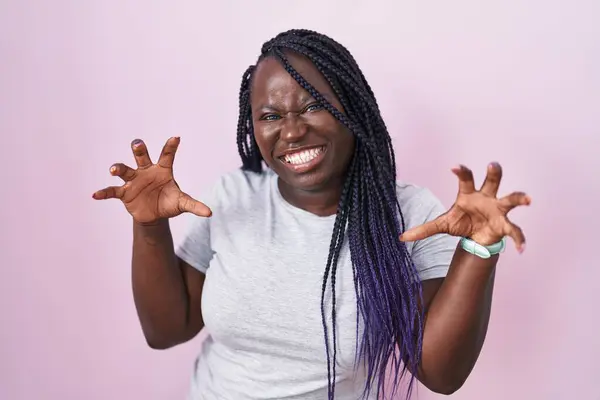 年轻的非洲女人站在粉红的背景上笑着笑着做爪子动作像猫一样 咄咄逼人 性感的表情 — 图库照片