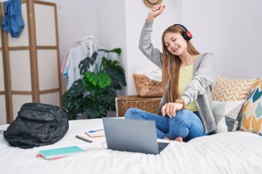 Genç beyaz kadın dans ediyor ve yatak odasında müzik dinliyor.