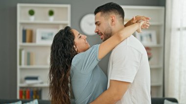 Erkek ve kadın çift evde öpüşürken birbirlerine sarılıyorlar.