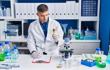 Genç İspanyol bilim adamı laboratuvarda kan testi tüpü tutuyor.