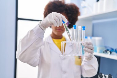 Laboratuvarda test tüpleri tutan Afrikalı Amerikalı kadın bilim adamı.